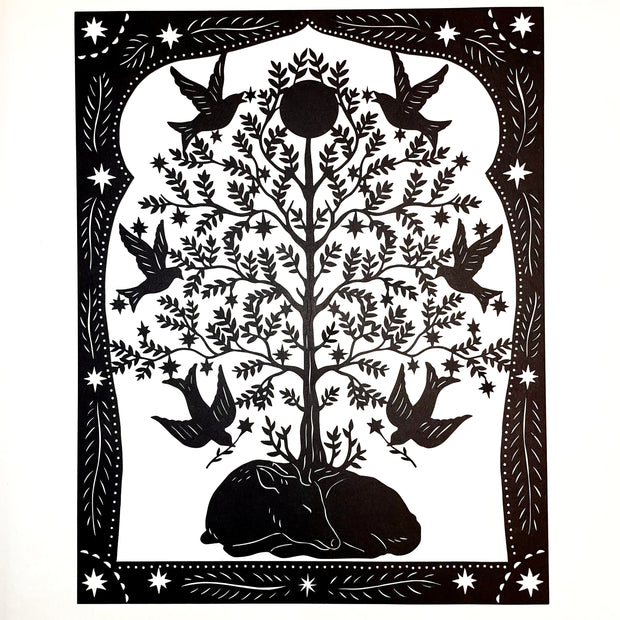Black paper cutting art of a deer, curled into itself and sleeping. A large tree grows atop of it, with many birds taking star shaped blossoms off the tree. Piece is framed wtih intricate cut paper border.
