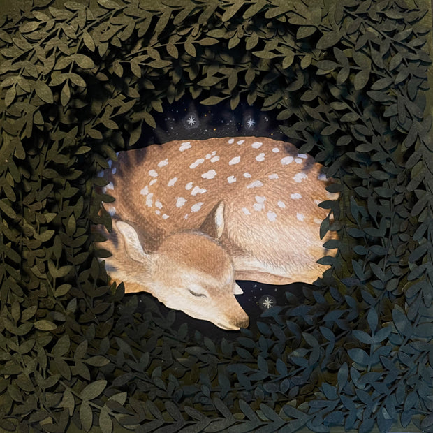 Layered cut paper diorama style sculpture, with many layers of leaves revealing a small scene of a sleeping doe.