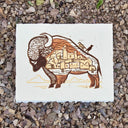 Artistic depiction of a buffalo with a village inside its body on a textured surface.