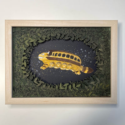 Paper cutting diorama of the Catbus from My Neighbor Totoro, flying though a starry night sky. The scene is framed with layers of cut leaves. 