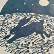 Simplistic outdoor night scene made of cut paper of a rabbit running with a carrot in its mouth. A full moon and stars are overhead and long stars and grass are on the ground. Close up to show small details.