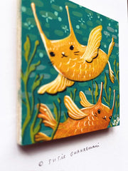 Painting of 2 fish, one yellow and one orange, both with cat faces. They swim over one another against a teal background with kelp.