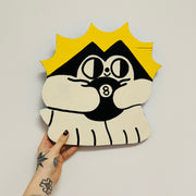Painted die cut wooden sculpture of a very stylized black and white cartoon cat, holding a magic 8 ball with a bright yellow cartoon sun behind it.