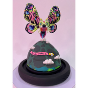 Mixed media sculpture of a large psychedelically colored moth, with large eyes hovering over a rounded land mass. A small helicopter flies around the mound with a banner that reads "All Hail"