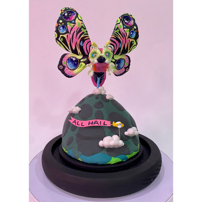 Mixed media sculpture of a large psychedelically colored moth, with large eyes hovering over a rounded land mass. A small helicopter flies around the mound with a banner that reads "All Hail"