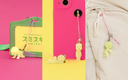 Yellow character charm on a pink phone case with a green card holder in the background.