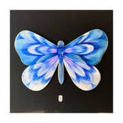 Illustration on cut out paper of a indigo butterfly with abstract striping on its wings, akin to a flower petals. Butterfly has gold outlining and is mounted on black paper.
