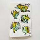 Several colorful inkblots on a paper. Black ink doodles go over the blots to make drawings, such as birds and an elephant.