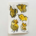 Several colorful inkblots on a paper. Black ink doodles go over the blots to make drawings, such as birds, a butterfly, a squirrel and a small horned animal.