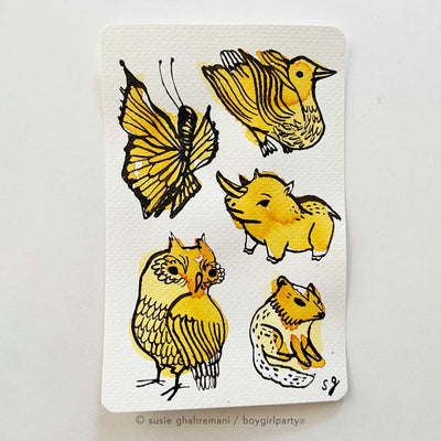 Several colorful inkblots on a paper. Black ink doodles go over the blots to make drawings, such as birds, a butterfly, a squirrel and a small horned animal.