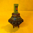 Decorative wooden object, shaped loosely like UFO with a colorful green Tiki head figure