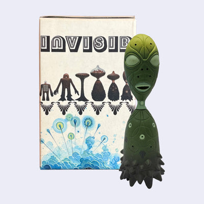 Green alien figure in front of product packaging for a blind box figure line.