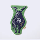 Die cut fabric coaster, shaped to the design of a dark blue jackalope, with a very large, wide body. Border is green. Backside of coaster, which is also the back view of the design.