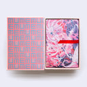 Hardcover box of postcards, open to reveal a grid style pattern within the box of "memu" written over and over. A red thread acts as a way to pull out the postcards.