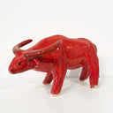 A glossy red ceramic bull figurine with curved horns, standing on a white surface against a white background.