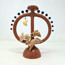Ceramic sculpture like a candelabra, circular in shape with a support structure running through the middle with rabbits and a moon on a white background