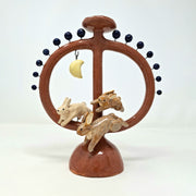 Ceramic sculpture like a candelabra, circular in shape with a support structure running through the middle with rabbits and a moon on a white background