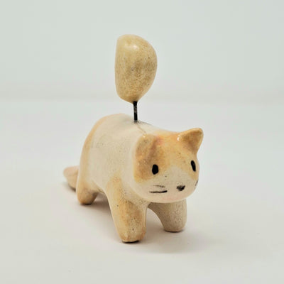 Ceramic cat figurine with a small yellow moon on its head, held up by a wire.