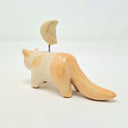 Ceramic cat figurine with a small yellow moon on its head, held up by a wire.
