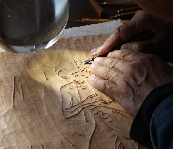Process photo showing an artist carving the woodblock to reveal a printable surface.