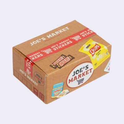Box of stickers, made to look like a cardboard shipping box holding Trader Joe's grocery items, with labeling and illustrations on the exterior that mimic the real thing.