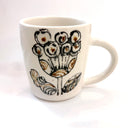 White mug with black floral design on a white background