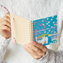 Person holding a notebook with a colorful cat design on the cover