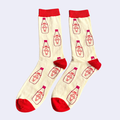 Pair of cream colored socks, with red tops, heels and toes. In a repeating pattern is a bottle of Kewpie Mayo with a small Big Boss Robot head over the logo.