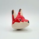 A small ceramic fox head ornament with a glossy red and cream finish, featuring black eyes and nose, set against a plain light gray background.