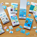 A set of colorful sticker sheets arranged on a light wood tabletop. The set includes multiple colorful printed sheets with cartoon animal illustrations and loose individual stamp pieces scattered around.