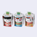 Three colorful ceramic cups with face designs in packaging on a white background