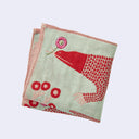 Sage green square handkerchief featuring graphic of a red Komodo dragon, holding a pink flower with its tongue. Below it are small pink trees with many branches and red circular flowers. Close up.