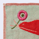 Sage green square handkerchief featuring graphic of a red Komodo dragon, holding a pink flower with its tongue. Below it are small pink trees with many branches and red circular flowers.