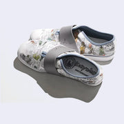 A pair of slip on white sneaker with various illustrations printed on the canvas surface. Illustrations are by Kozyndan, using imagery of Amsterdam cityscapes and animals.