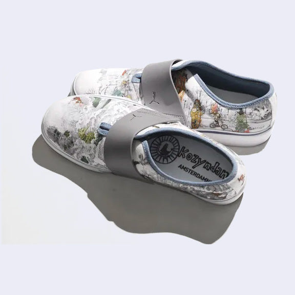A pair of slip on white sneaker with various illustrations printed on the canvas surface. Illustrations are by Kozyndan, using imagery of Amsterdam cityscapes and animals.