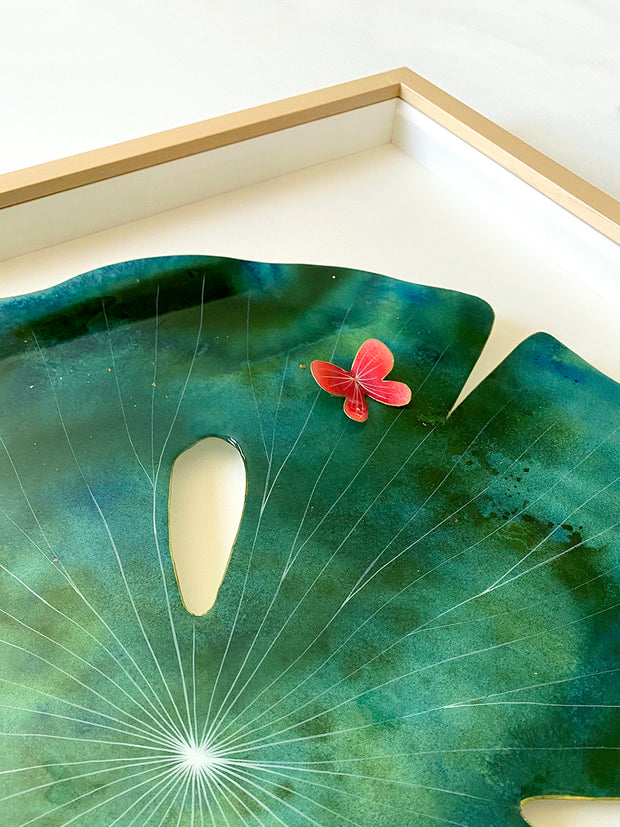 Painting on cut paper of a round blue and green marbled pattern lily pad, with thin white lines and a shiny resin coating. A small red butterfly sits atop the pad. Displayed at an angle to show sheen of resin.