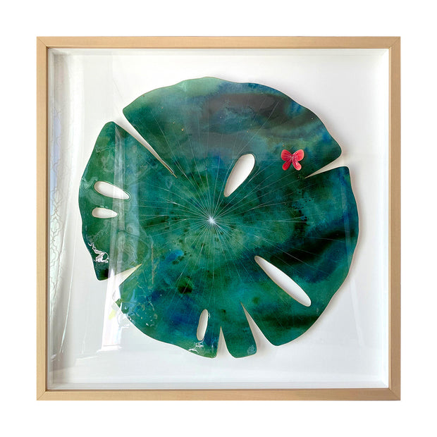Painting on cut paper of a round blue and green marbled pattern lily pad, with thin white lines and a shiny resin coating. A small red butterfly sits atop the pad. Piece is in a thin, light wood grain frame.