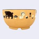 Yellow bowl with cream and brown colored illustrations of a small bird and forest greenery (flowers, grass, butterflies)