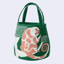 Green tote bag with a pink lemur design sitting on a tree on a white background.