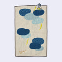 Cream colored rectangle shaped towel with rounded shapes to represent several thunder clouds, with rain coming out of them and 2 lightning bolts. Atop the upper right cloud is a small gray yokai god character, producing a lightning bolt of its own.