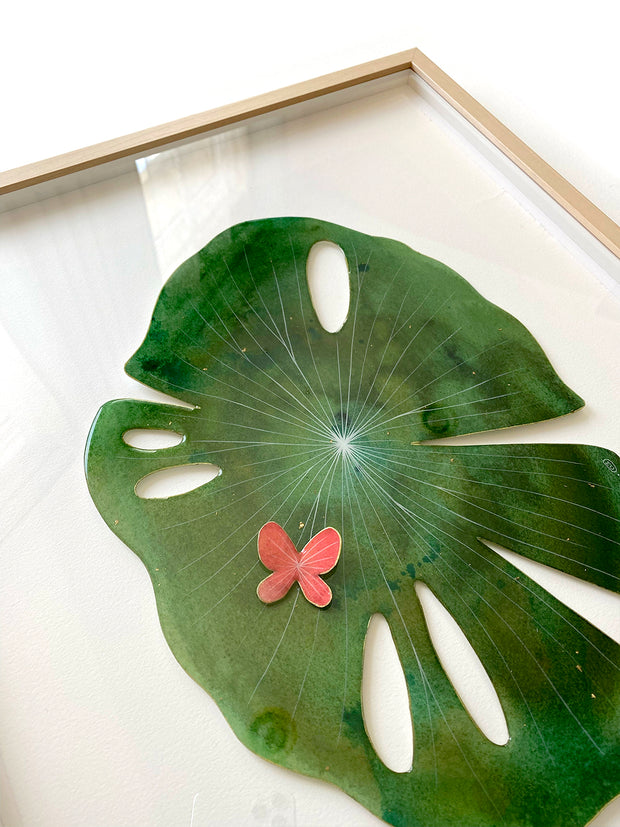 Painted cut out lily pad leaf coated in resin, green with subtle marbling pattern and thin white stripes. A small red butterfly rests atop the leaf.  Displayed at an angle to show sheen of resin.