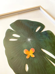 Painted cut out lily pad leaf, dark green with subtle marbling pattern and thin white stripes. A small orange butterfly rests atop the leaf. Displayed at an angle to show sheen of resin coating.