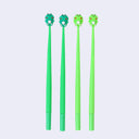 Four green pens with frog-shaped tips on a light purple background
