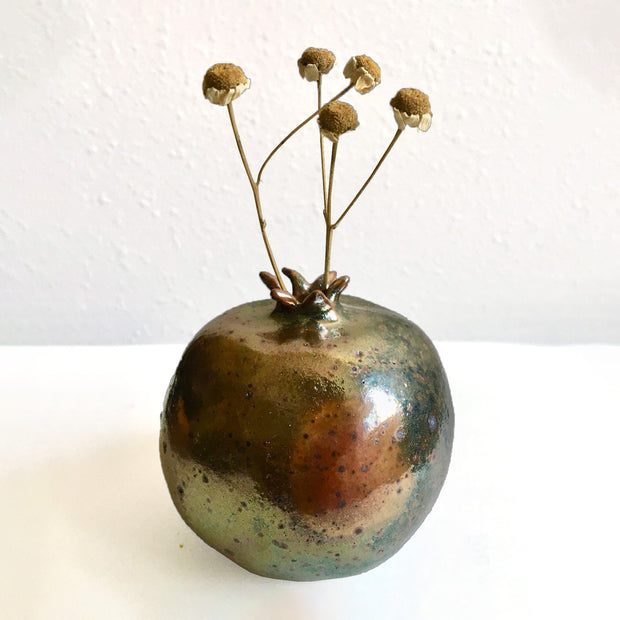 Brown ceramic sculpture of a pomegranate.