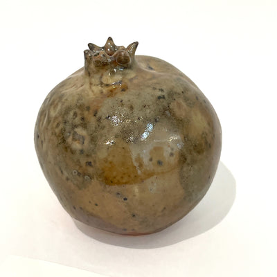 Brown ceramic sculpture of a pomegranate.