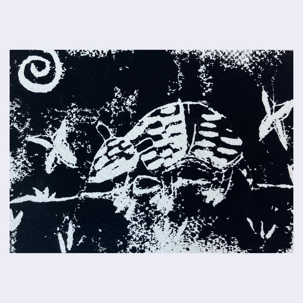 Inky print on textured paper of a small armadillo, with swirl and star symbols around.