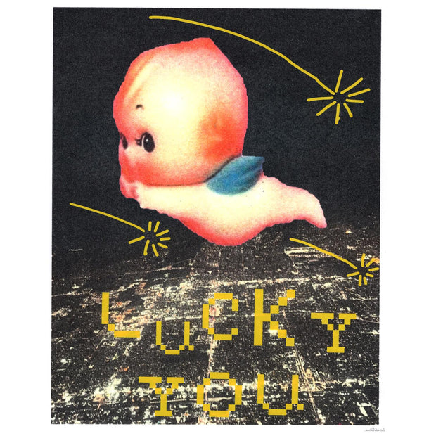 Screenprint of a lit up city at night, seen from overhead and far away as if in a plane. A large Kewpie baby flies overhead, with yellow shooting stars and pixilated text that reads "Lucky You."