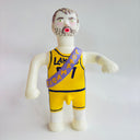 Figurine wearing a yellow basketball jersey with a purple sash on a white background