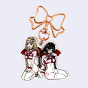 Acrylic keychain with an illustration of 2 mostly nude girls, bound in pink rope with small red devil horns and wings. Keychain is attached to a rose gold tone bow.