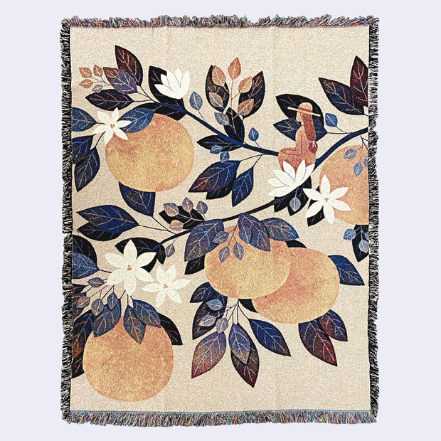 Cream color woven tapestry blanket featuring an illustration of a small woman, her back facing the viewer, sitting on a single branch of a series of large orange tree branches. Leaves are orange, dark blue and deep reddish purple and the oranges are a soft orange. 